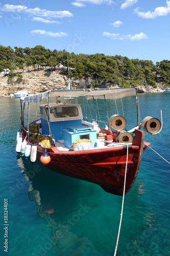Traditional wooden fishing boat anchored in picturesque fishing village and small port of Votsi, Alonissos island, Sporades, Greece © aerial-drone