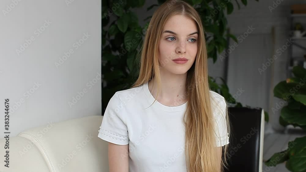 Smiling young woman blogger influencer sit on sofa looking at camera make video conference call recording vlog at home Smiling young woman blogger influencer sit on sofa looking at camera make video conference call recording vlog at home