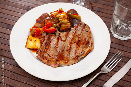 Tasty fried beef steak served with eggplants baked with bell peppers, onion and tomatoes
