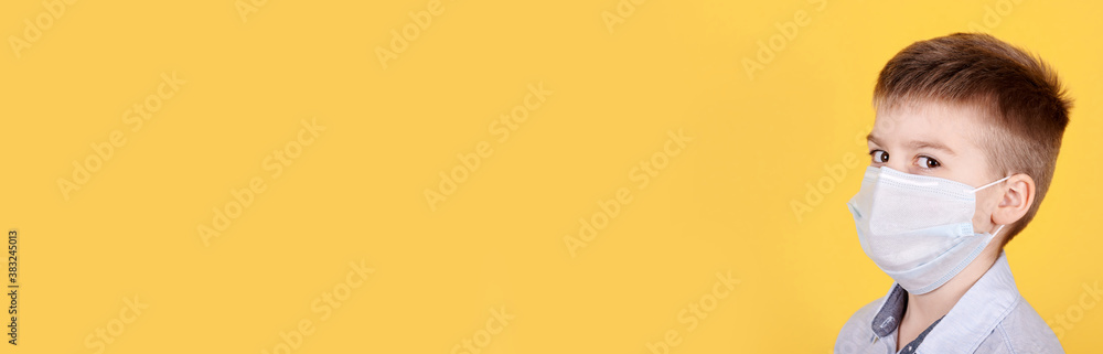 Portrait of a brunette boy in medical mask. Isolated on yellow background, copy space template, banner.