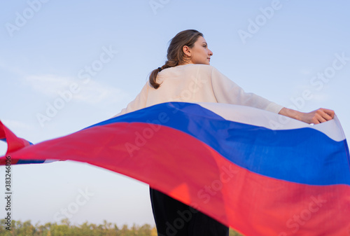 Russian flag. Back view of a woman walking with a flag in nature. Symbol of independence and patriotism of the Russian Federation