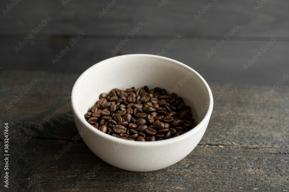 Bowl filled of fresh arabica or robusta coffee beans on a wooden table. Bowl filled of fresh arabica or robusta coffee beans on a wooden table.