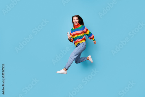 Full length body size profile side view of her she nice attractive cheerful cheery girl wearing casual jumping running using device 5g app fast speed free time isolated blue pastel color background