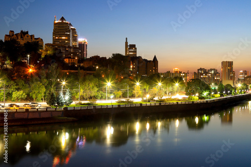 A picturesque beautiful view of modern buildings, skyscrapers, towers of a big city at night. The embankment is reflected in the River in the evening. Dnipro, Dnepropetrovsk, Ukraine