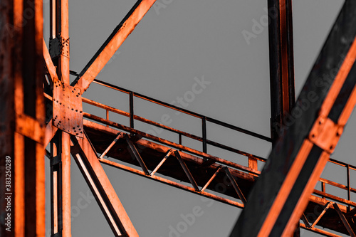 Old gas structure in dangerous area. Details of joints and rivets under a warm sunset, orange natural lighting, remains of the industrial revolution in Europe, steel framework aged and textured.