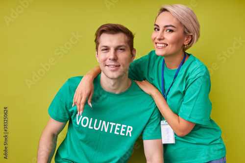 friendly man and woman keen on charity, caucasian friends in green t-shirts look at camera and smile, volunteering