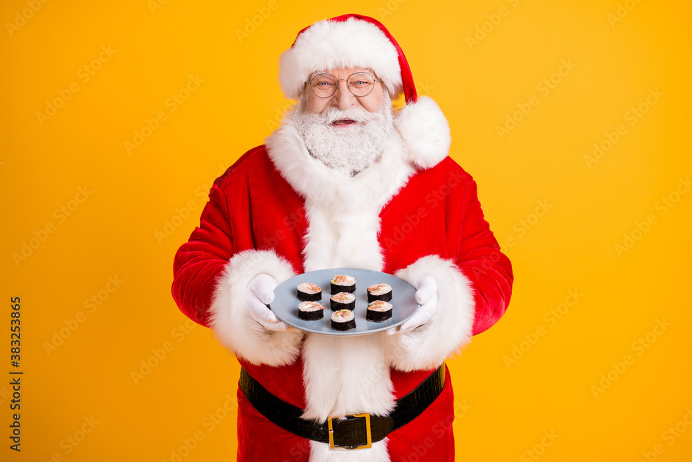 Portrait of his he nice cheerful cheery funny glad white-haired Santa holding in hands homemade domestic fresh tasty yummy sushi meal isolated bright vivid shine vibrant yellow color background