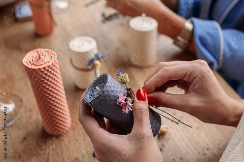 Obraz na płótnie DIY wax candle making process. Woman making decorative wax candle and decorates with dried flowers, close-up of hands w salonie