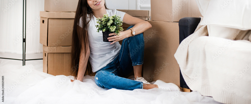 young woman with a home plant sitting on the floor in the new l