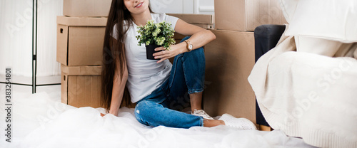 Obraz na płótnie young woman with a home plant sitting on the floor in the new l w salonie