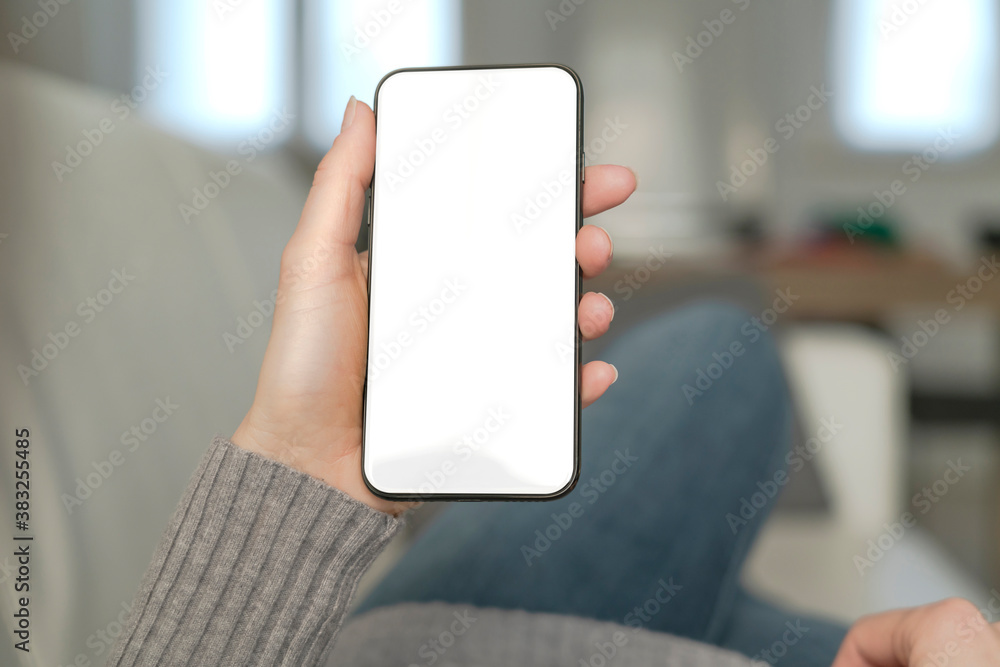 Template mockup smartphone with white screen. A pretty woman use the smartphone for socialize and shopping online on the sofa at home.