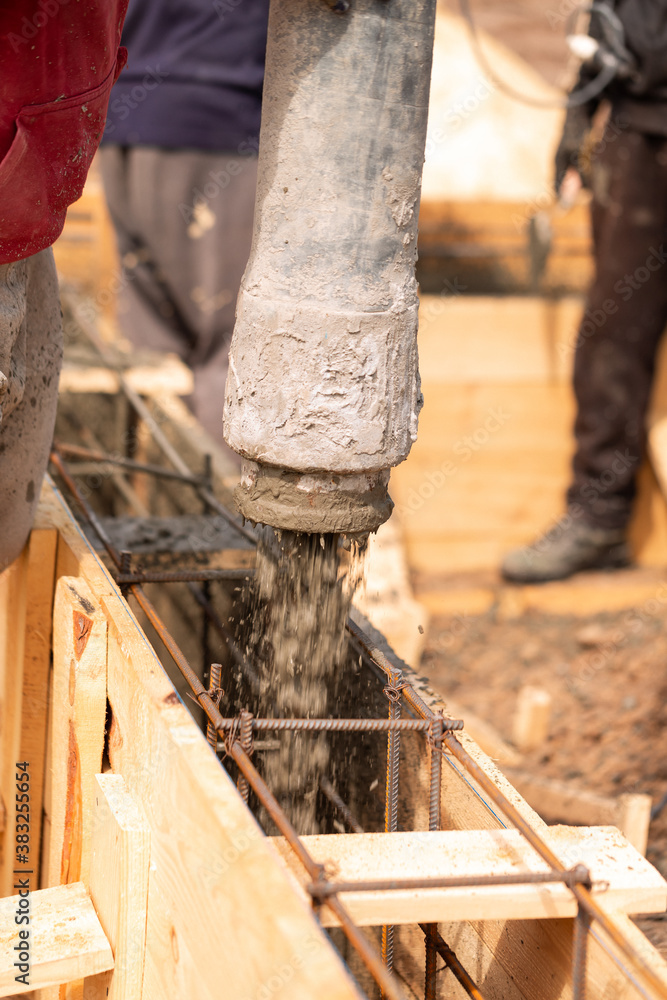 Close up of construction worker laying cement or concrete into the foundation formwork with automatic pump