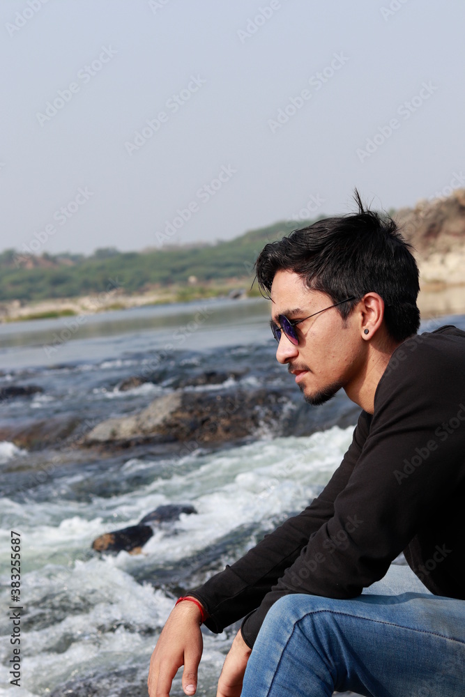 Young indian man sitting at river side