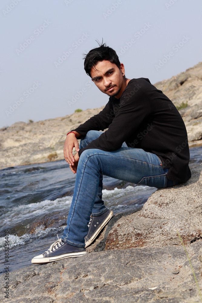 Young indian man sitting at river side Young indian man sitting at river side