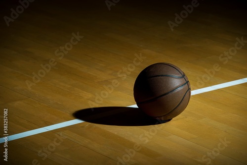 Basketball On Hardwood Court Floor With Spot Lighting. Workout online concept