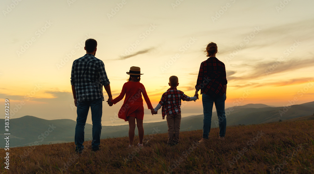 Happy family: mother, father, children son and daughter stand with their backs holding hands on sunset. Happy family: mother, father, children son and daughter stand with their backs holding hands on sunset.