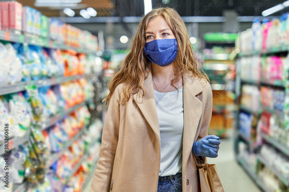 Shopping during the coronavirus Covid-19 pandemic. Woman in facial mask and rubber gloves buys grocery things at supermarket.