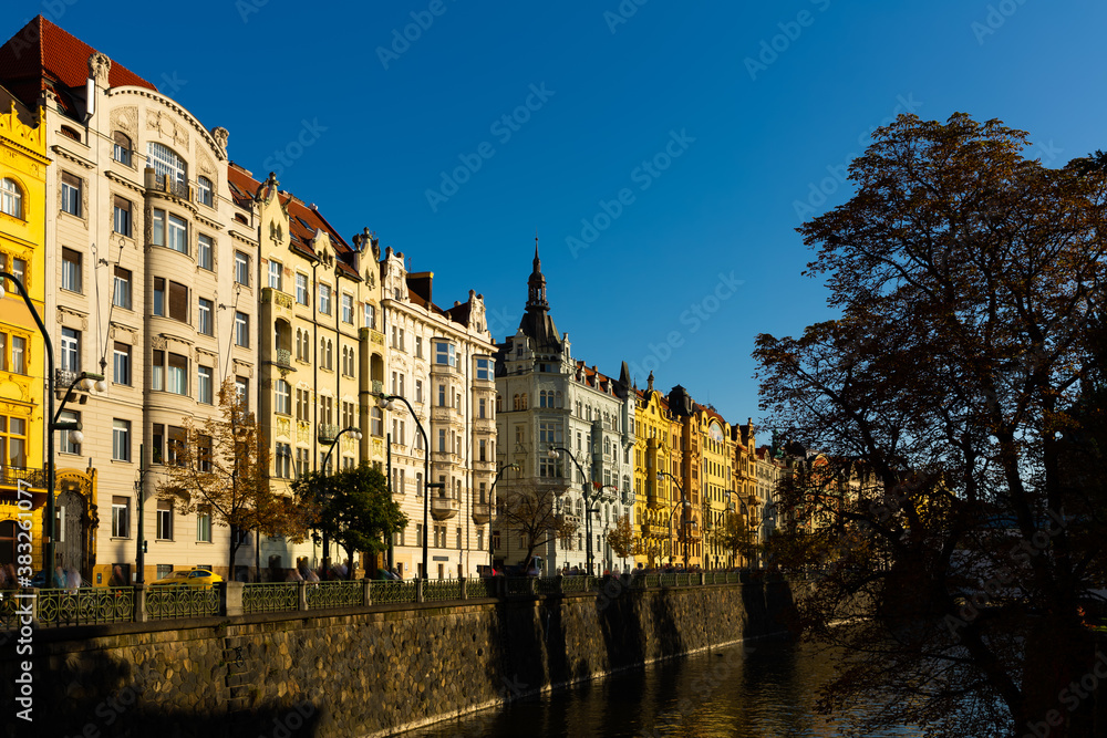Picturesque view of Prague embankment on bank of Vltava river with peculiar architecture on autumn day, Czech Republic