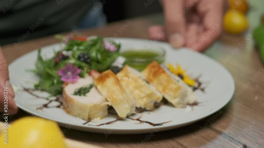 Table with fresh vegetables, spices and chicken roll with spinach nicely served on a plate with greens, flower decorations and green oil Table with fresh vegetables, spices and chicken roll with spinach nicely served on a plate with greens, flower decorations and green oil