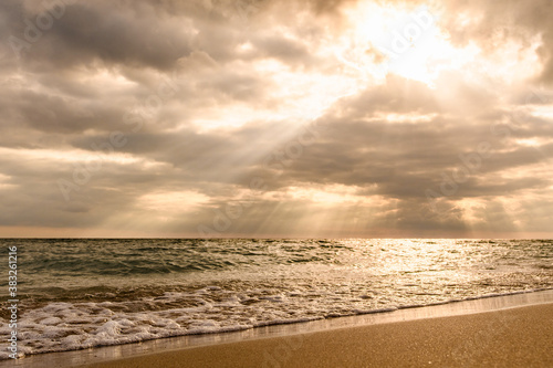 Beautiful sunset on the seashore. The sun's rays shine through the clouds. Focusing on the water's edge.