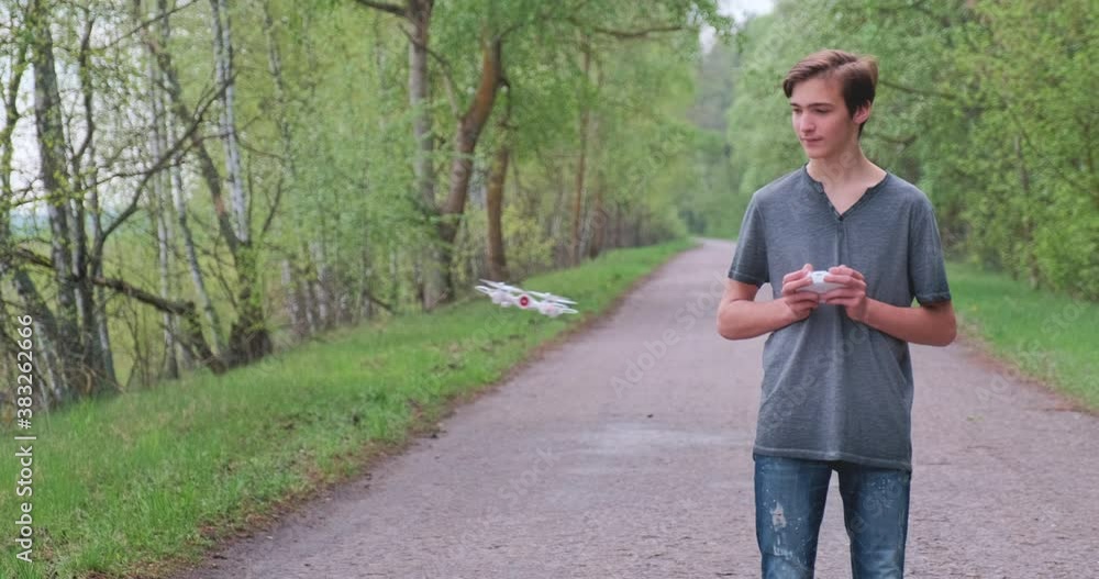 Boy lifts the drone using the remote control. Teenager launches a drone in the open air. Young man plays with a quadrocopter in nature. White boy learns to fly a drone in a Park. Slow motion video. Boy lifts the drone using the remote control. Teenager launches a drone in the open air. Young man plays with a quadrocopter in nature. White boy learns to fly a drone in a Park. Slow motion video.