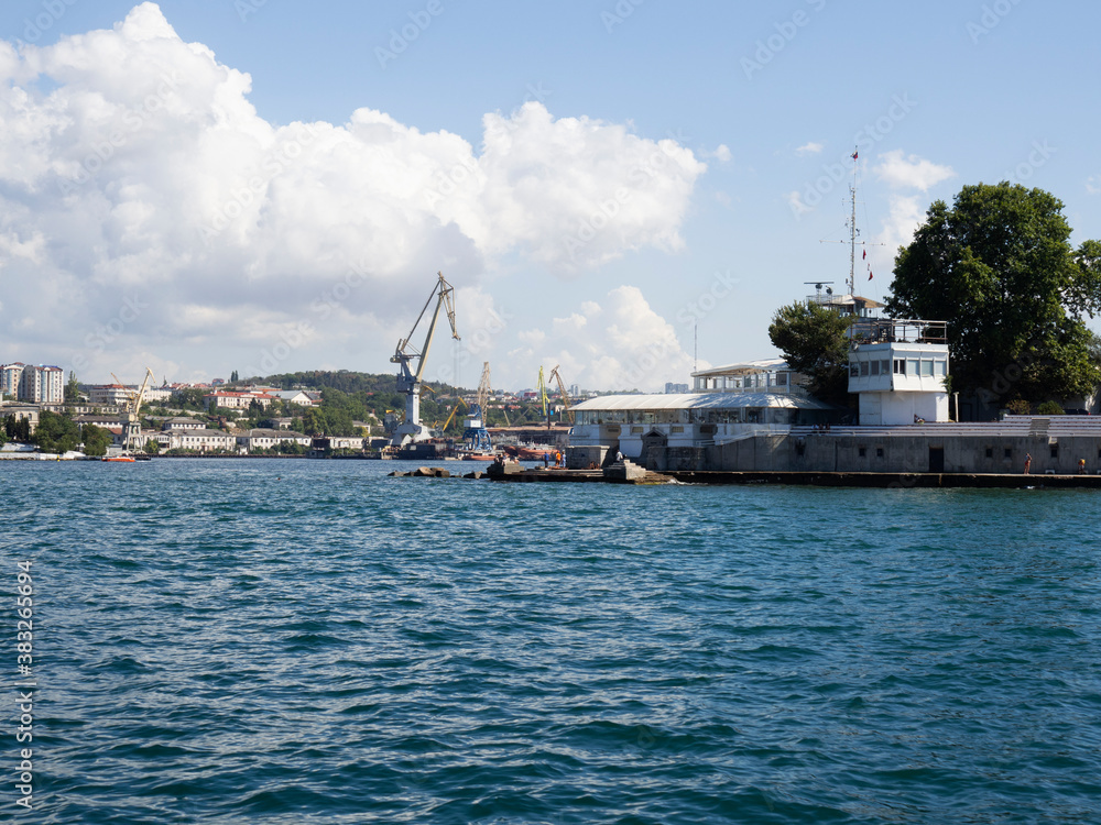 Черное море в далеке плавующий ремонтный док для кораблей, отдыхающие загарают и купаются на камнях возле берега