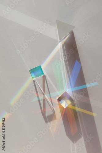 Glass geometric figures prisms with light diffraction of spectrum colors and complex reflection with trendy light and hard shadows on a white background