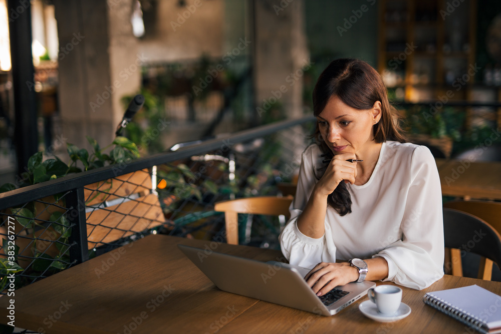 Woman sitting alone, working online, at cafe.
