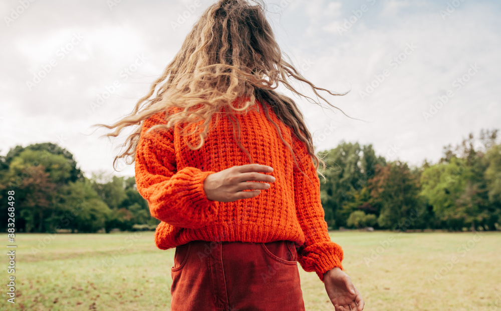 © iuricazac - Horizontal image of an young woman with blowing long blonde hair wearing an orange sweater posing on the sky and nature background. Pretty female playing with her hair outdoor in the park. © iuricazac - Horizontal image of an young woman with blowing long blonde hair wearing an orange sweater posing on the sky and nature background. Pretty female playing with her hair outdoor in the park.