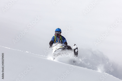 snowmobilers make a turn in a snow-white valley. COPY SPACE. Extreme Snowmobile Ride & Racing. a bright suit and a snow motorcycle. snowmobilers sports riding. high resolution photo