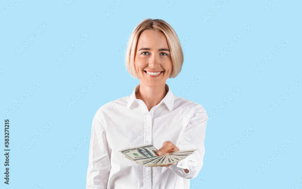 Portrait of smiling business lady holding lots of money over blue studio background, panorama Portrait of smiling business lady holding lots of money over blue studio background, panorama