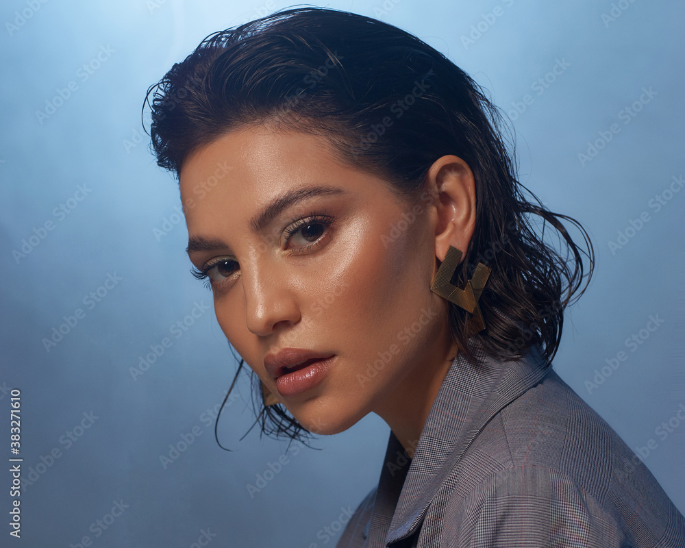 Closeup fashion face studio portrait. Tanned caucasian brunette woman. Fashionable stylish female model with makeup and wet hair against smoke at background - obrazy, fototapety, plakaty 