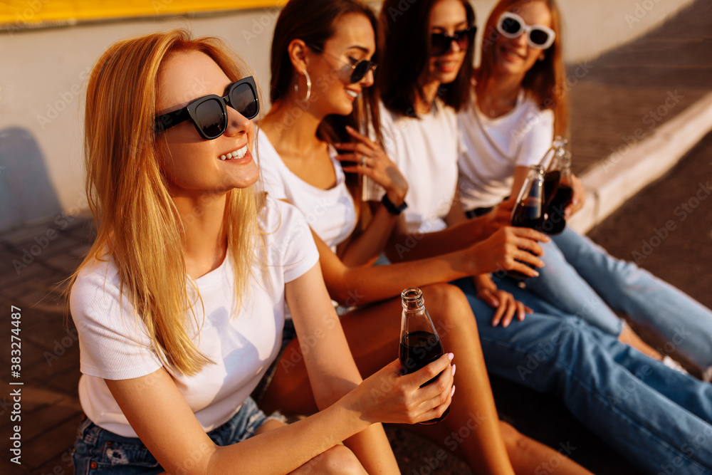 Young happy friends drinking a drink and having fun together on a sunny summer day against the background of a yellow wall, concept of friendship and celebration Young happy friends drinking a drink and having fun together on a sunny summer day against the background of a yellow wall, concept of friendship and celebration