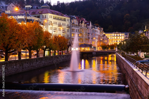 Scenic view of illuminated embankment of Czech spa town of Karlovy Vary on autumn night ..