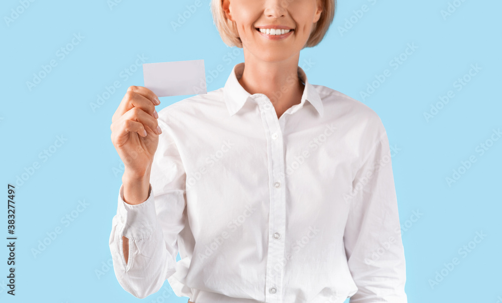Close up of female entrepreneur showing empty business card with space for design over blue studio background, panorama Close up of female entrepreneur showing empty business card with space for design over blue studio background, panorama