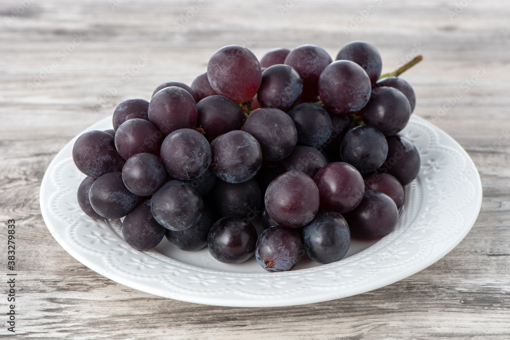 Delicious bunch of grapes fruit on a plate over wooden table background. Delicious bunch of grapes fruit on a plate over wooden table background.