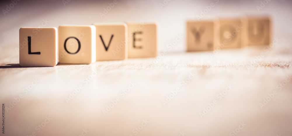 Love you word made of tiles on dark wooden background Love you word made of tiles on dark wooden background