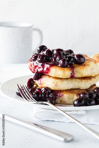 Warm blueberry sauce on top of a fluffy pancake stack ready for eating.