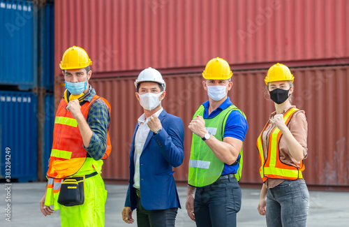 Engineer and worker team wearing protection face mask against coronavirus, Happy business people team celebration with blurred cargo containers background