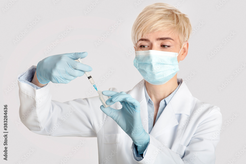 Treatment, health care and medical staff. Middle aged woman looks at syringe Treatment, health care and medical staff. Middle aged woman looks at syringe