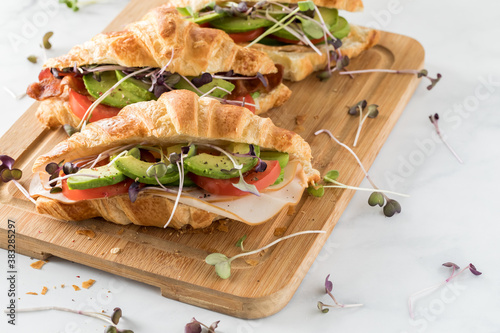 Valokuva Three freshly made croissant sandwiches on a wooden board ready for eating