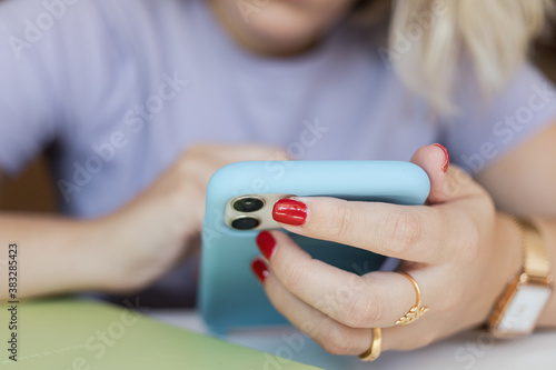 Woman holding her mobile phone while take notes. Work from home concept