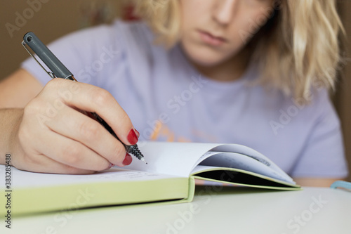Woman holding her mobile phone while take notes. Work from home concept
