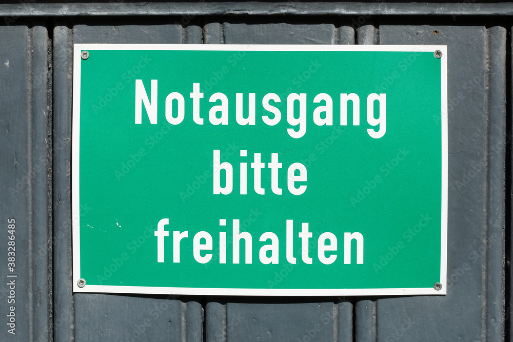 Grünes Schild Notausgang bitte freihalten an einer dunklen Holztür, Deutschland Grünes Schild Notausgang bitte freihalten an einer dunklen Holztür, Deutschland