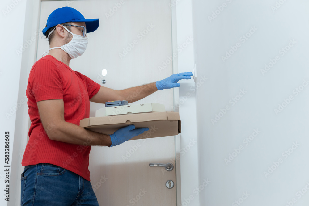 Delivery guy with protective mask holding pizza box at the door. Delivery guy with protective mask holding pizza box at the door.