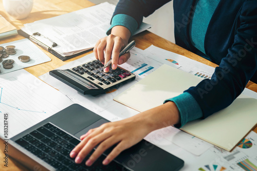 Tablou pe pânză Woman accountant use calculator and computer with holding pen on desk in office