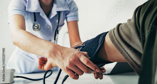 Nurse measuring arterial blood pressure man patient in hospital. Health care concept