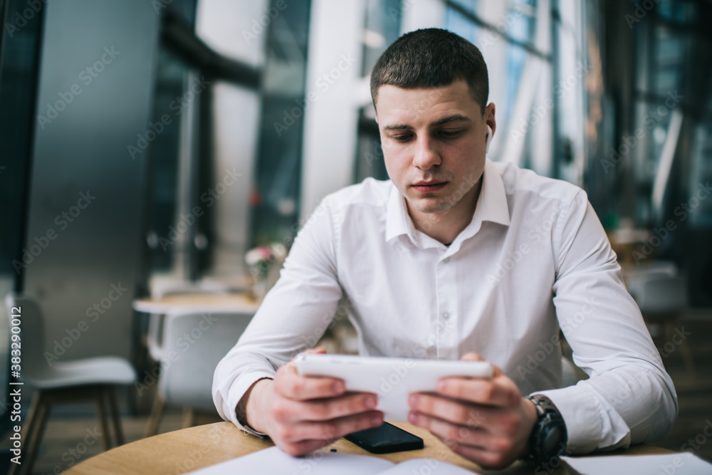 Young man with wireless earphones watching video on digital tablet Young man with wireless earphones watching video on digital tablet