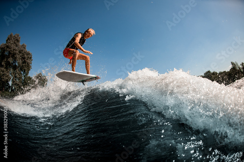 Beautiful view of guy on surf style wakeboard masterfully jumping over splashing wave
