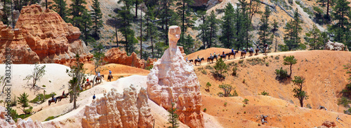 Bryce Canyon , Utah, USA: group of 16 horseriders riding neatly in a row along fascinating red, white and pink rock formations. 